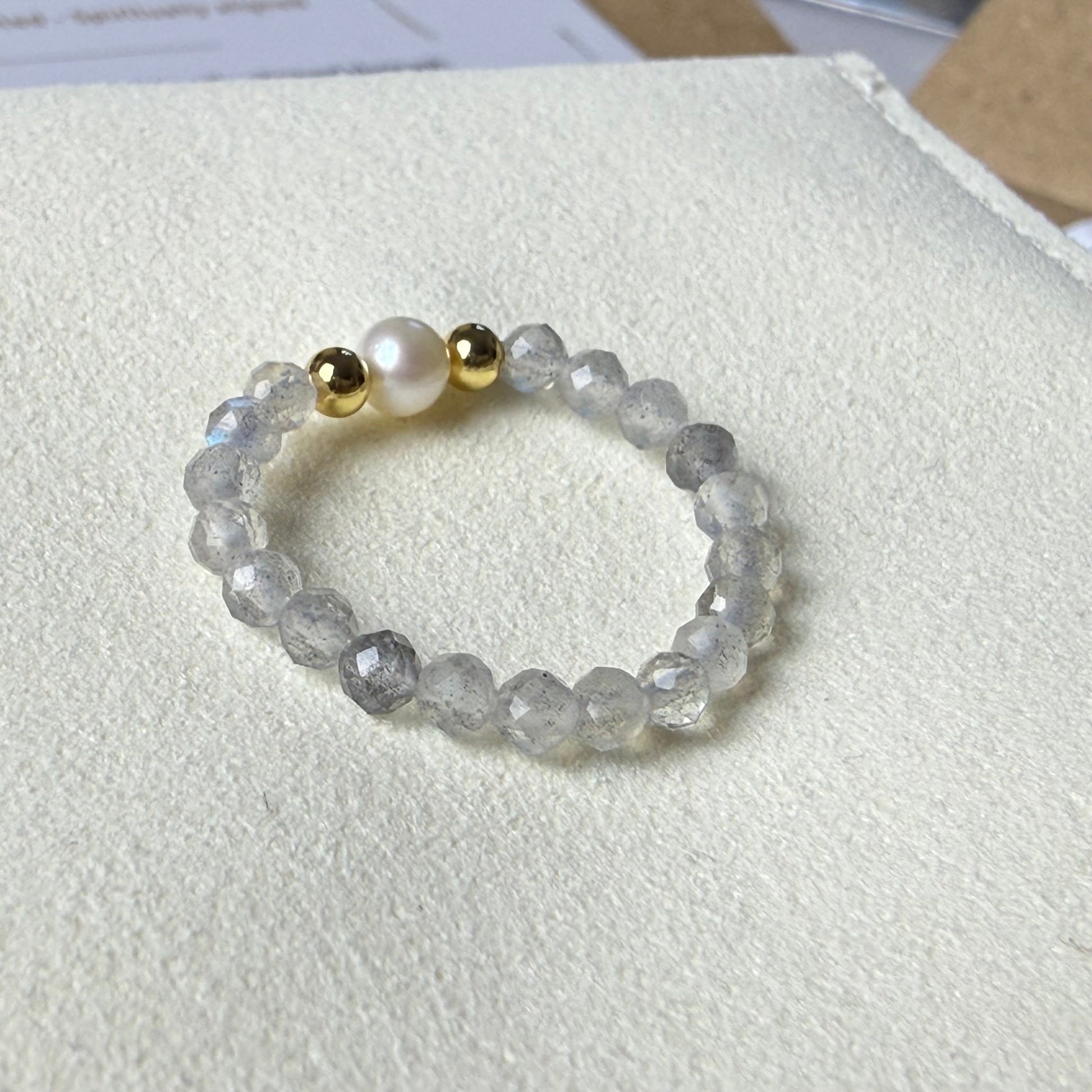 Close-up of iridescent grey labradorite beads showing blue flash with freshwater pearl and gold accents – Manushaa Gems