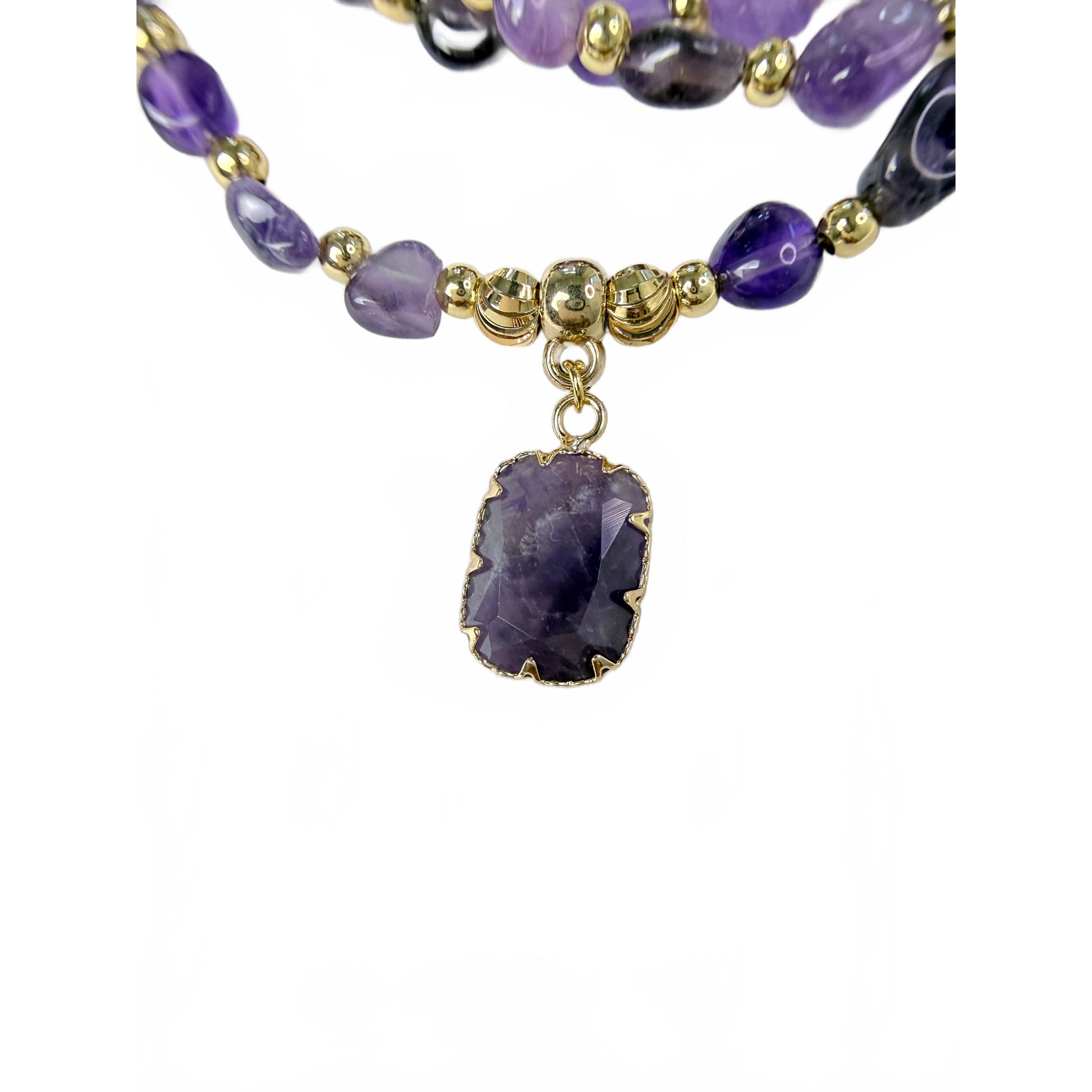 Close-up of the natural amethyst pendant in a gold claw setting, showing crystal banding and fluted gold beads