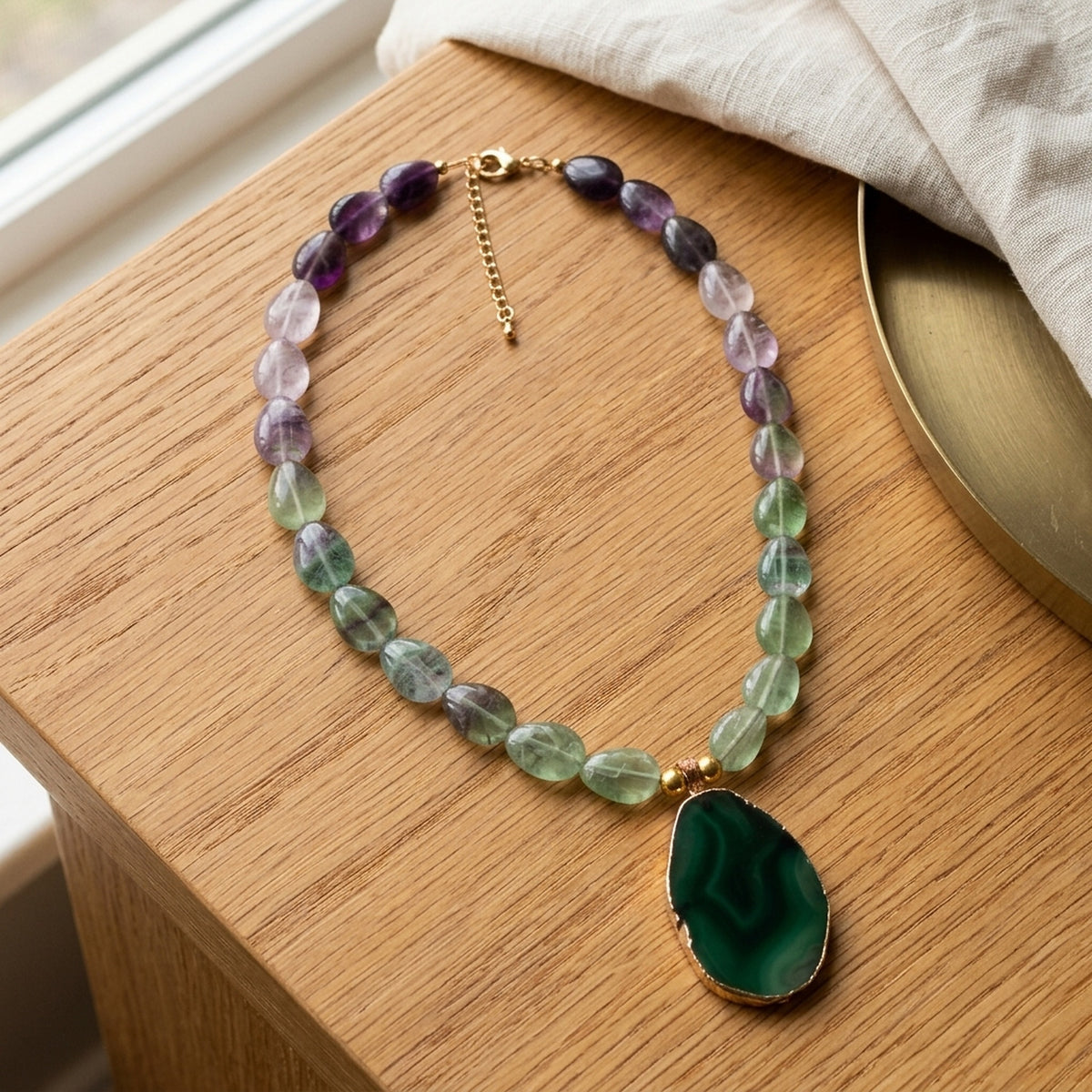 Fluorite and green agate necklace displayed on warm oak
