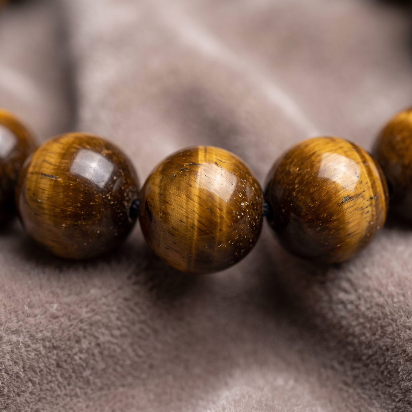 Macro close-up of golden Tiger's Eye 8mm crystal beads showing chatoyant shimmer