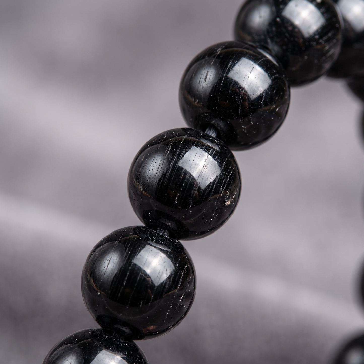Macro close-up of glossy Black Tourmaline 8mm crystal beads with natural striations