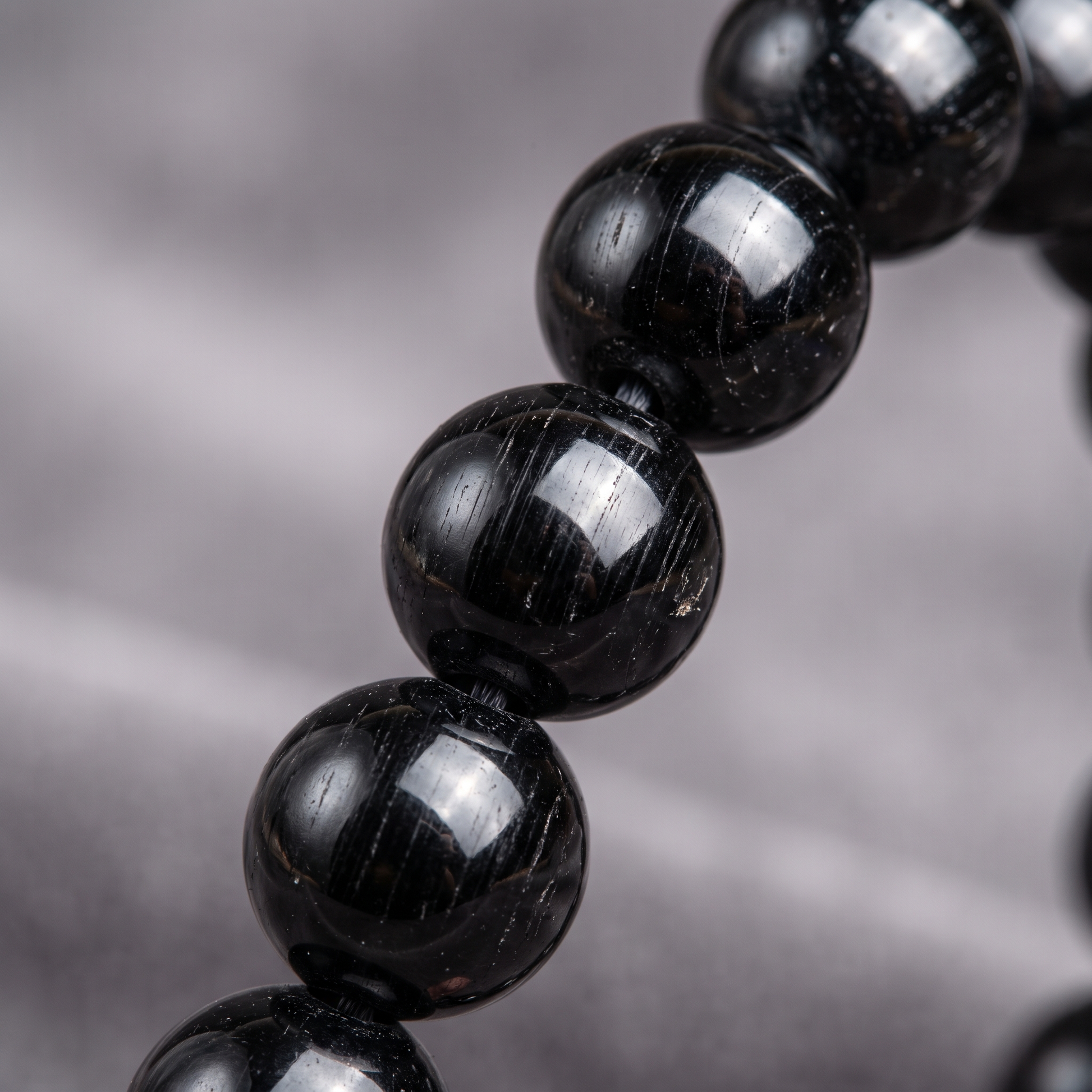 Macro close-up of glossy Black Tourmaline 8mm crystal beads with natural striations