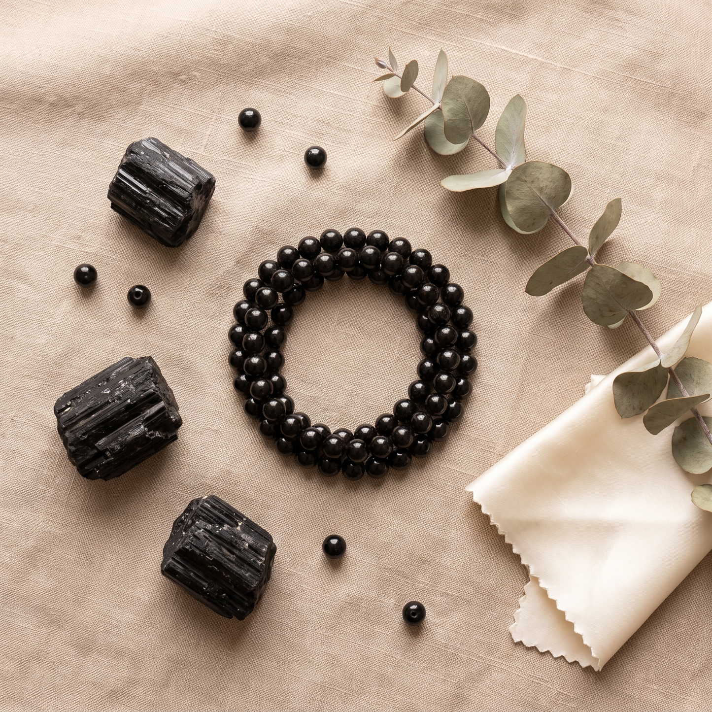 Black Tourmaline crystal bracelet flat lay with raw tourmaline chunks - luxury styling