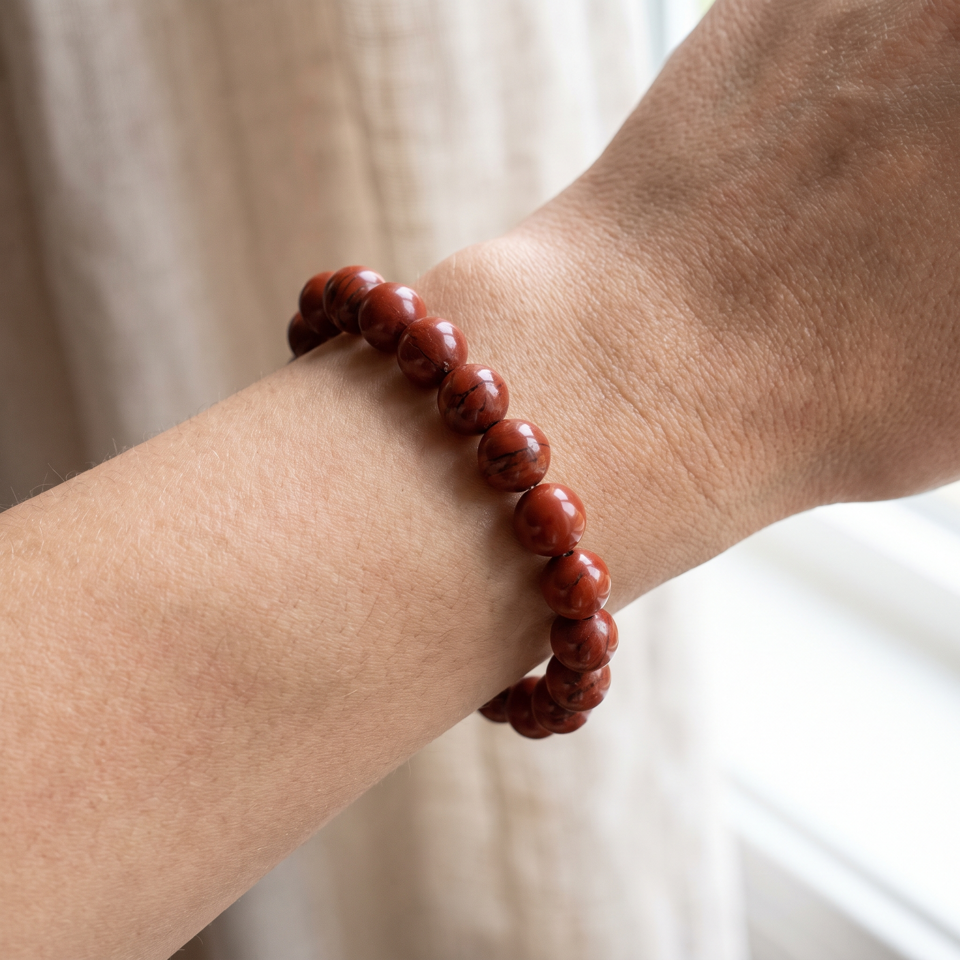 Red Jasper 10mm bead size reference shown on wrist - Manushaa Gems