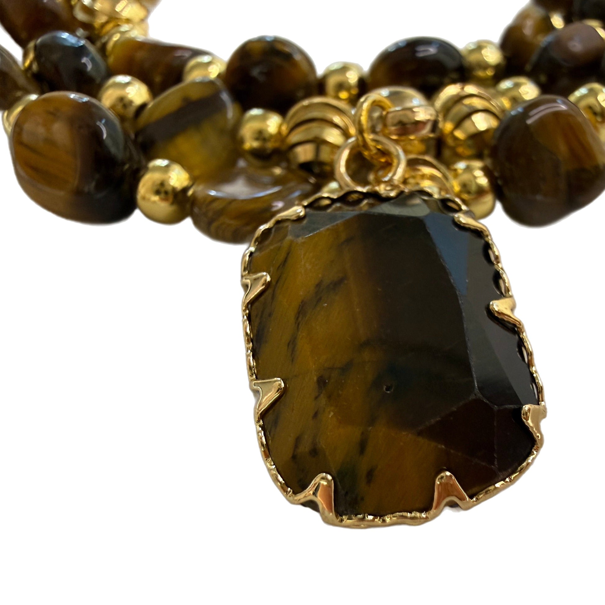 Close-up of the natural tiger eye pendant in a gold claw setting, showing the golden chatoyant band across the stone