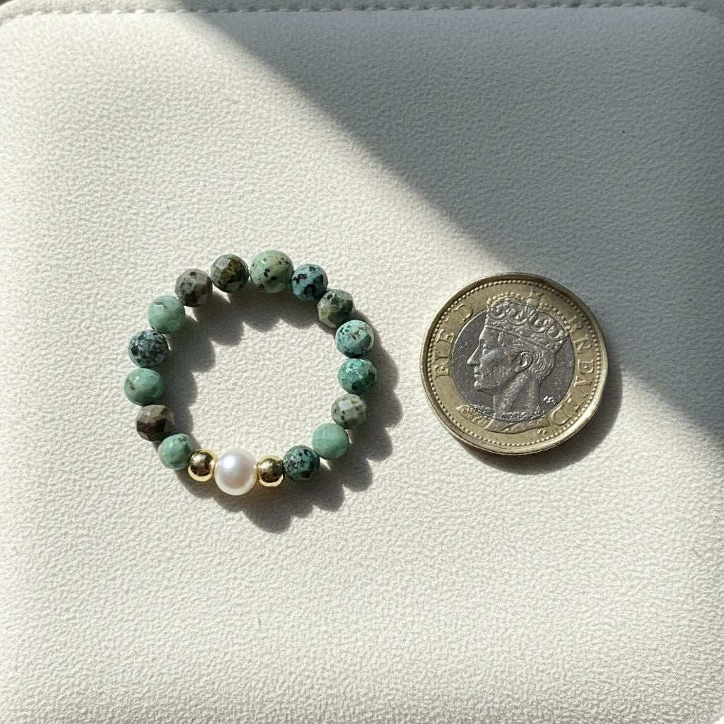 African turquoise and freshwater pearl stretch ring beside a one pound coin for scale – Manushaa Gems