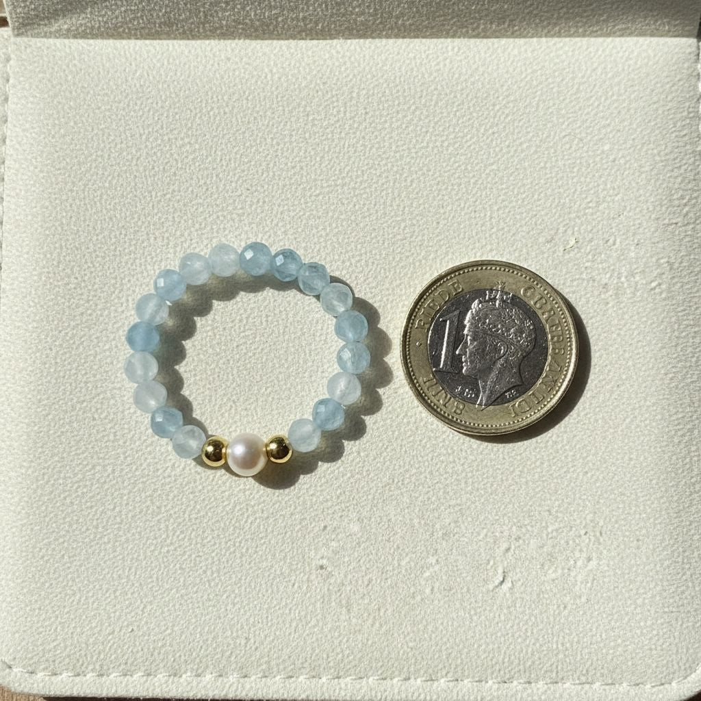 Aquamarine and freshwater pearl stretch ring beside a one pound coin for scale – Manushaa Gems
