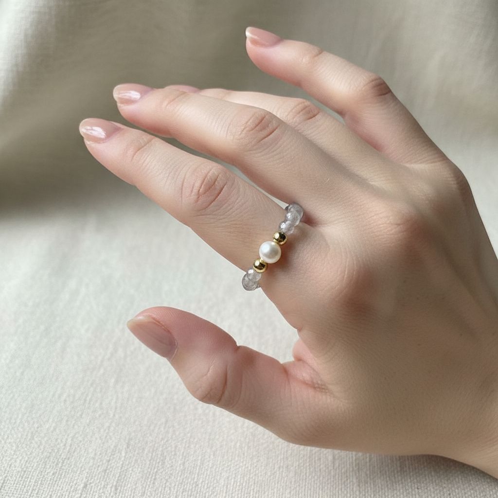 Woman's hand wearing grey labradorite and freshwater pearl stretch ring in soft daylight – Manushaa Gems