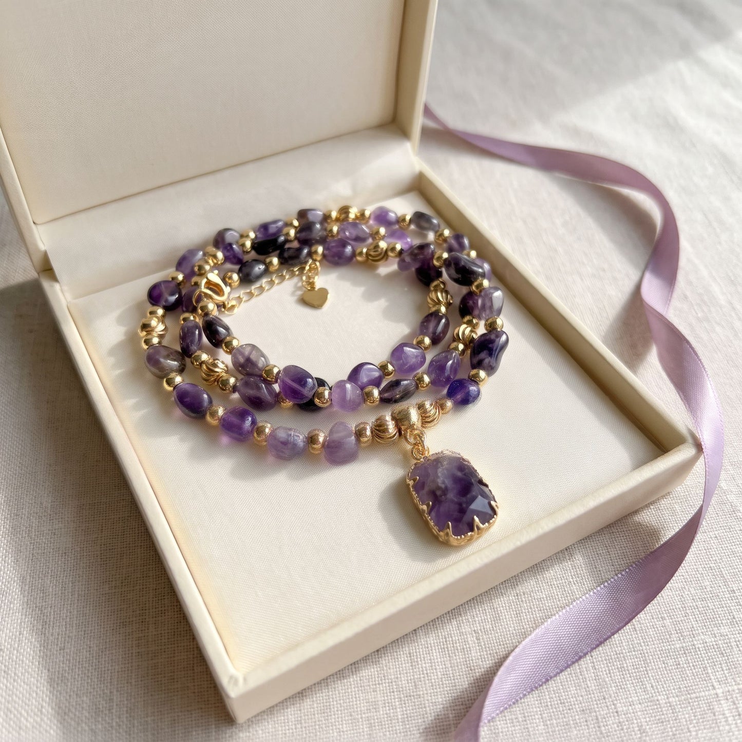 Amethyst healing crystal necklace presented in a cream gift box with a lilac ribbon