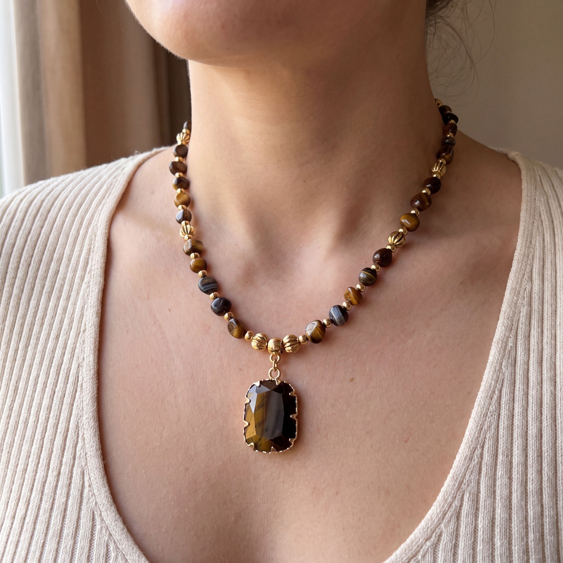 Woman wearing the natural tiger eye healing crystal necklace, 45cm length with gold pendant at the collarbone