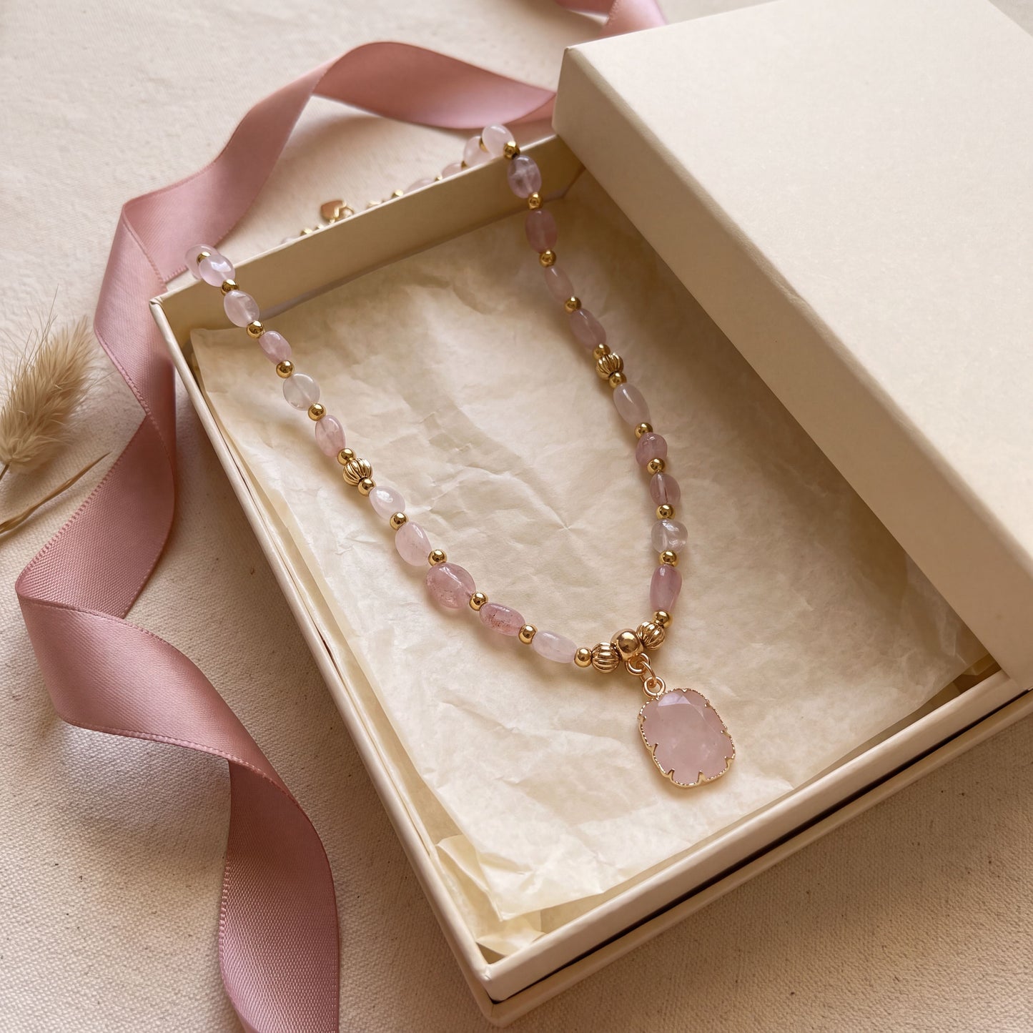 Rose quartz healing crystal necklace presented in a cream gift box with a blush pink satin ribbon