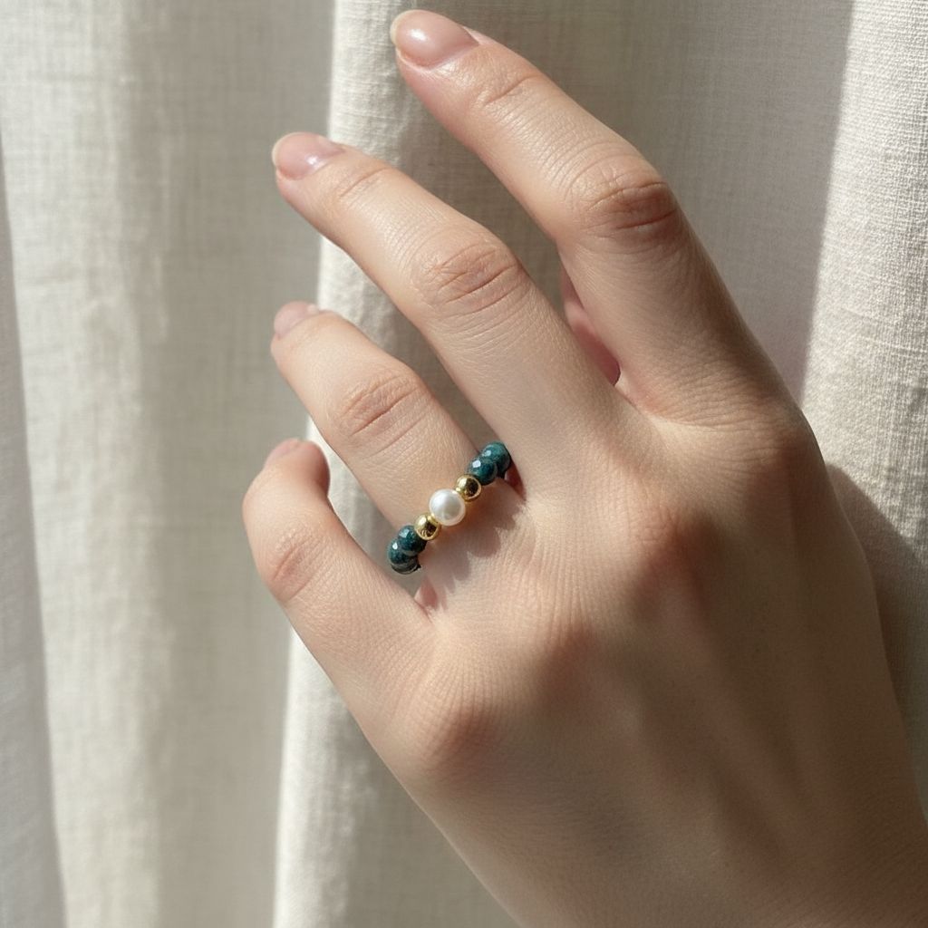 Woman's hand wearing blue-green azurite and freshwater pearl stretch ring in soft daylight – Manushaa Gems