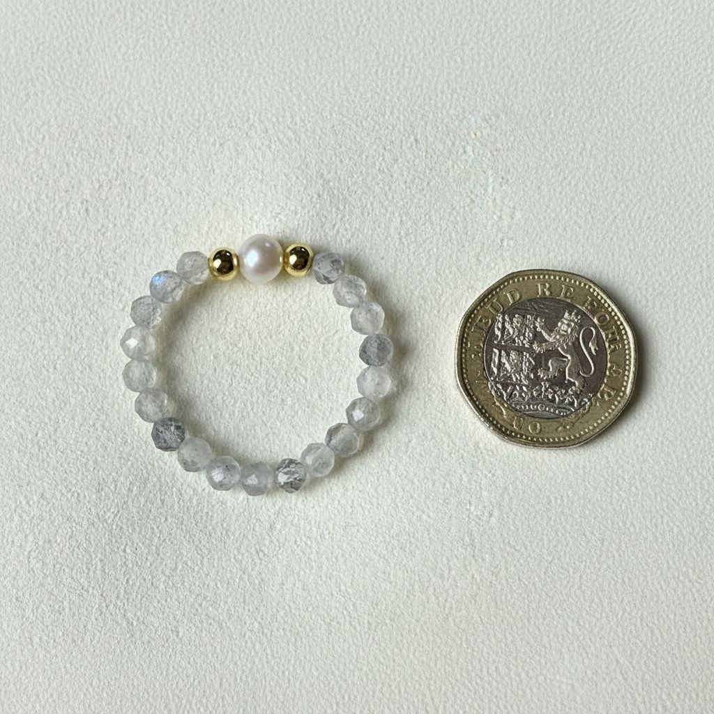 Grey labradorite and freshwater pearl stretch ring beside a one pound coin for scale – Manushaa Gems