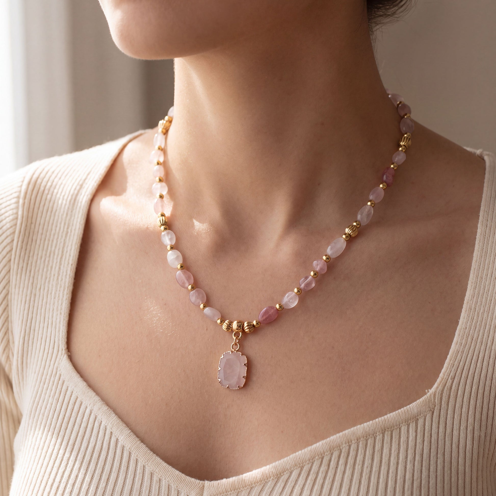 Woman wearing the natural rose quartz healing crystal necklace, 45cm length with gold pendant at the collarbone
